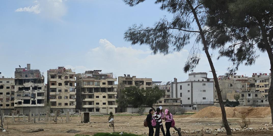 Landscape with destroyed houses and group of young people standing infant
