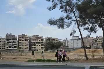 damaged houses in Damascus with people in front 