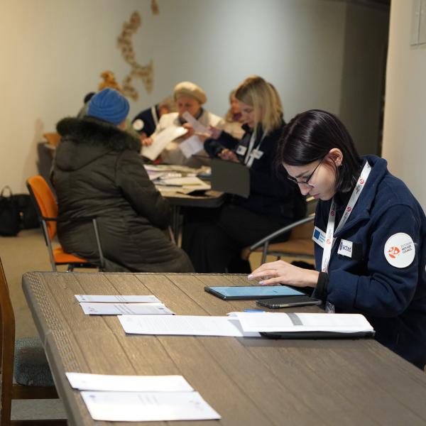 Woman sitting behind a desk with other people in the background 