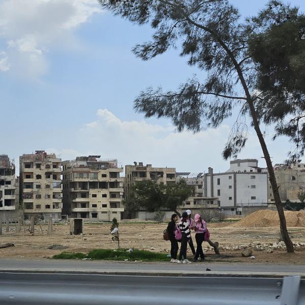 damaged houses in Damascus with people in front 